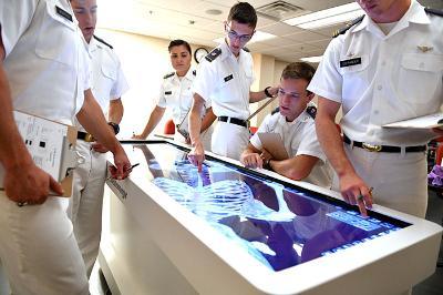 A group of cadets look at a virtual image of the human body