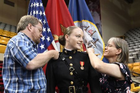 Female cadet at VMI receives US Marine Corps insignia pins from family during Commissioning
