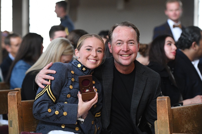 A female student (cadet) at VMI poses with her class ring and family member.