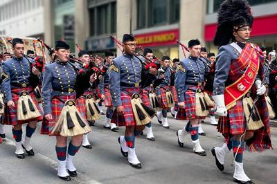 Members of the VMI Pipe Band march in tartan uniform playing bagpipes New York City.