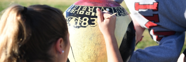 Cadets paint a cannonball on post to display their class ring design.