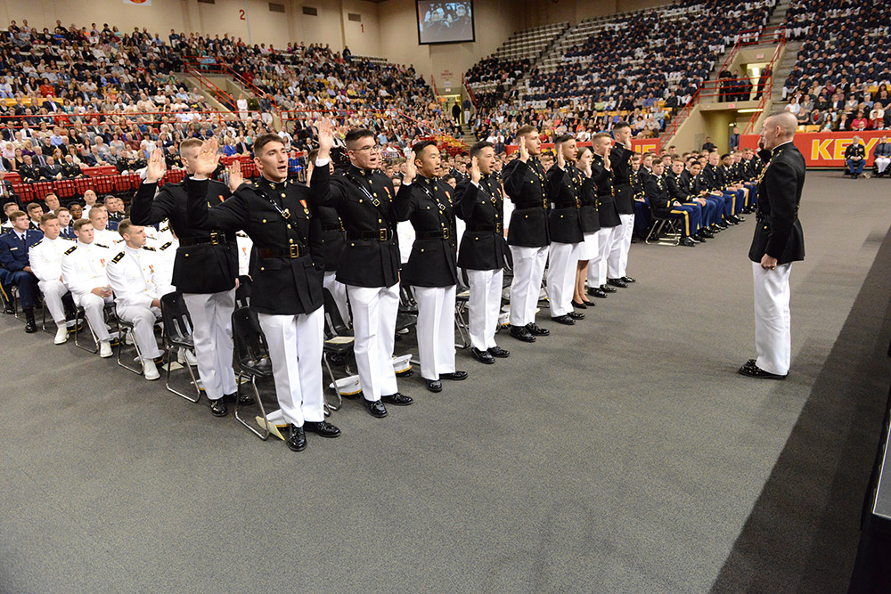 Cadets commissioning into the U.S. Marine Corps stand to take the oath.