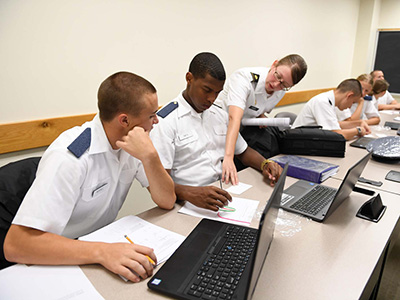 Maj. Amy Givler assists two cadets with a Wikisticks activity.