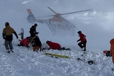 Skiers, including Erik Gottman ’25, assist avalanche victims on mountain in snow. Helicopter in the background.