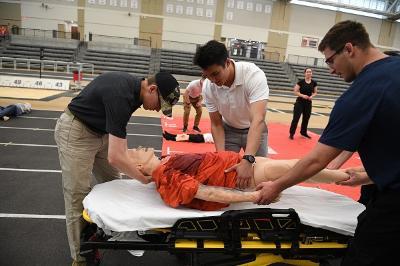 Cadets in EMT training place a mannequin victim on a gurney before wheeling it to an ambulance. —VMI Photo by Kelly Nye.