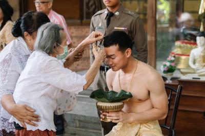 The grandmother of Kanokpon “Gun” Mettasat ’27 clips a lock of his hair during the haircut ritual last June in Thailand. –Photo courtesy of Kanokpon “Gun” Mettasat ’27.