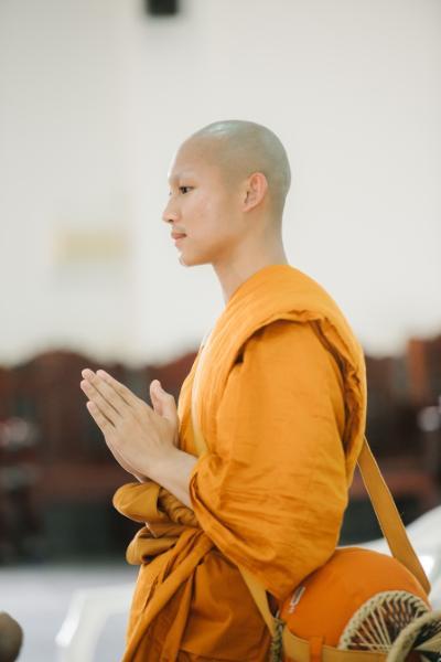 Kanokpon “Gun” Mettasat ’27 wears the traditional orange robe of a Buddhist monk.